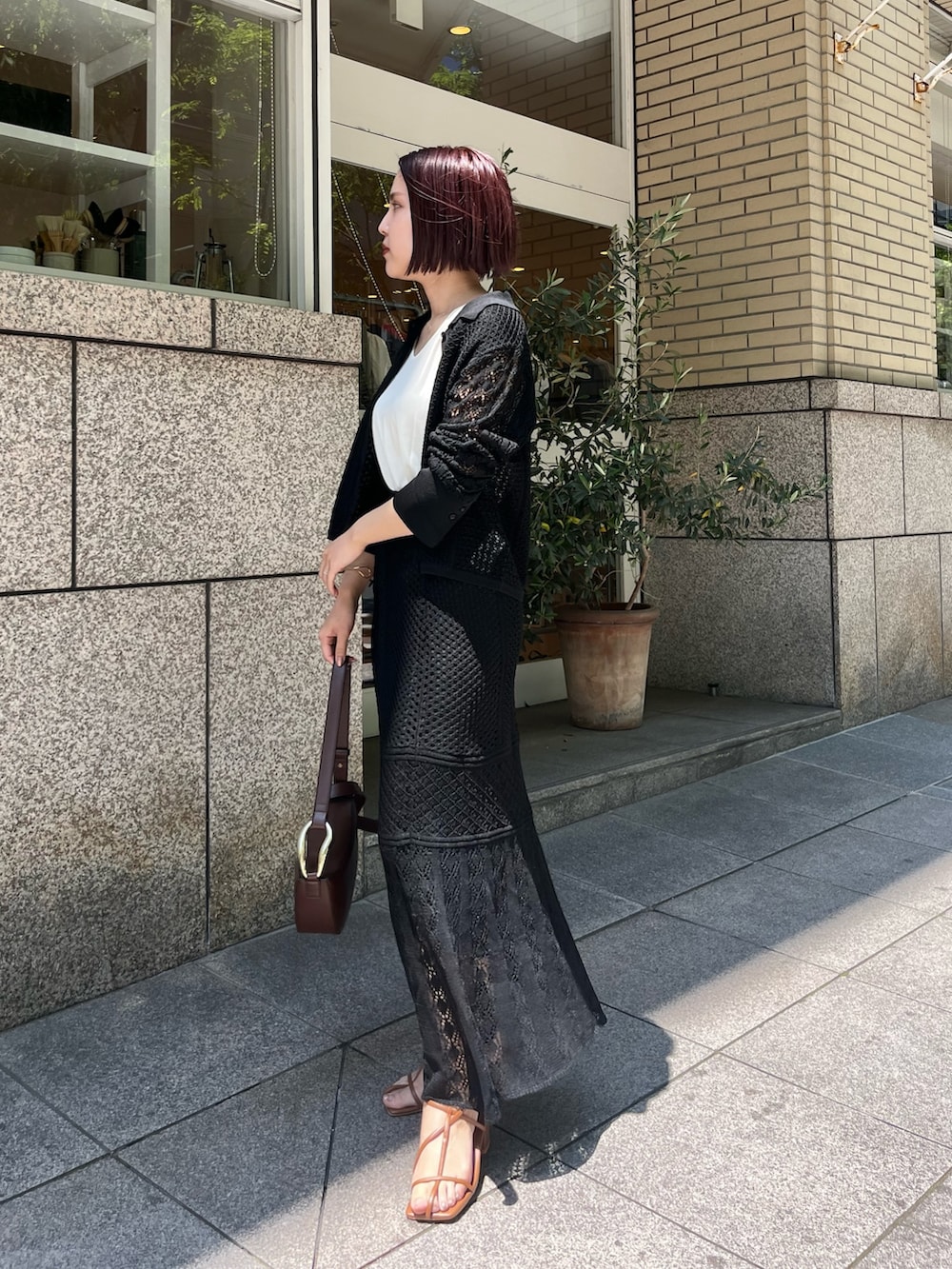 ブラック系のスカート、ブラウン系のショルダーバッグ、イエロー系のサンダルを着用したレディースの春コーディネートの2枚目の写真