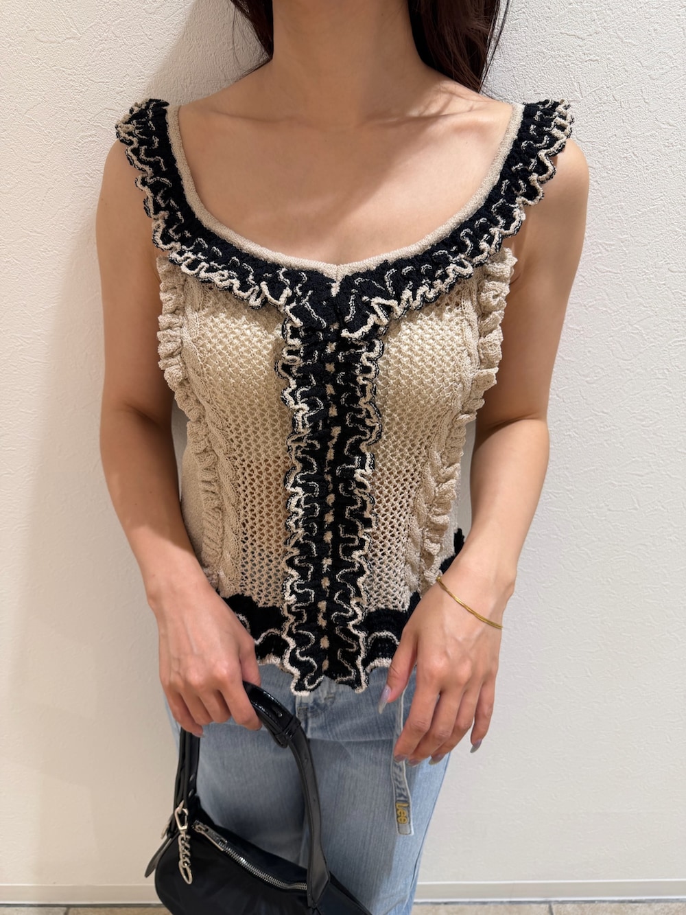 ブルー系のデニムパンツ、ベージュ系のニット/セーター、ブラック系のハンドバッグを着用したレディースの夏コーディネートの6枚目の写真