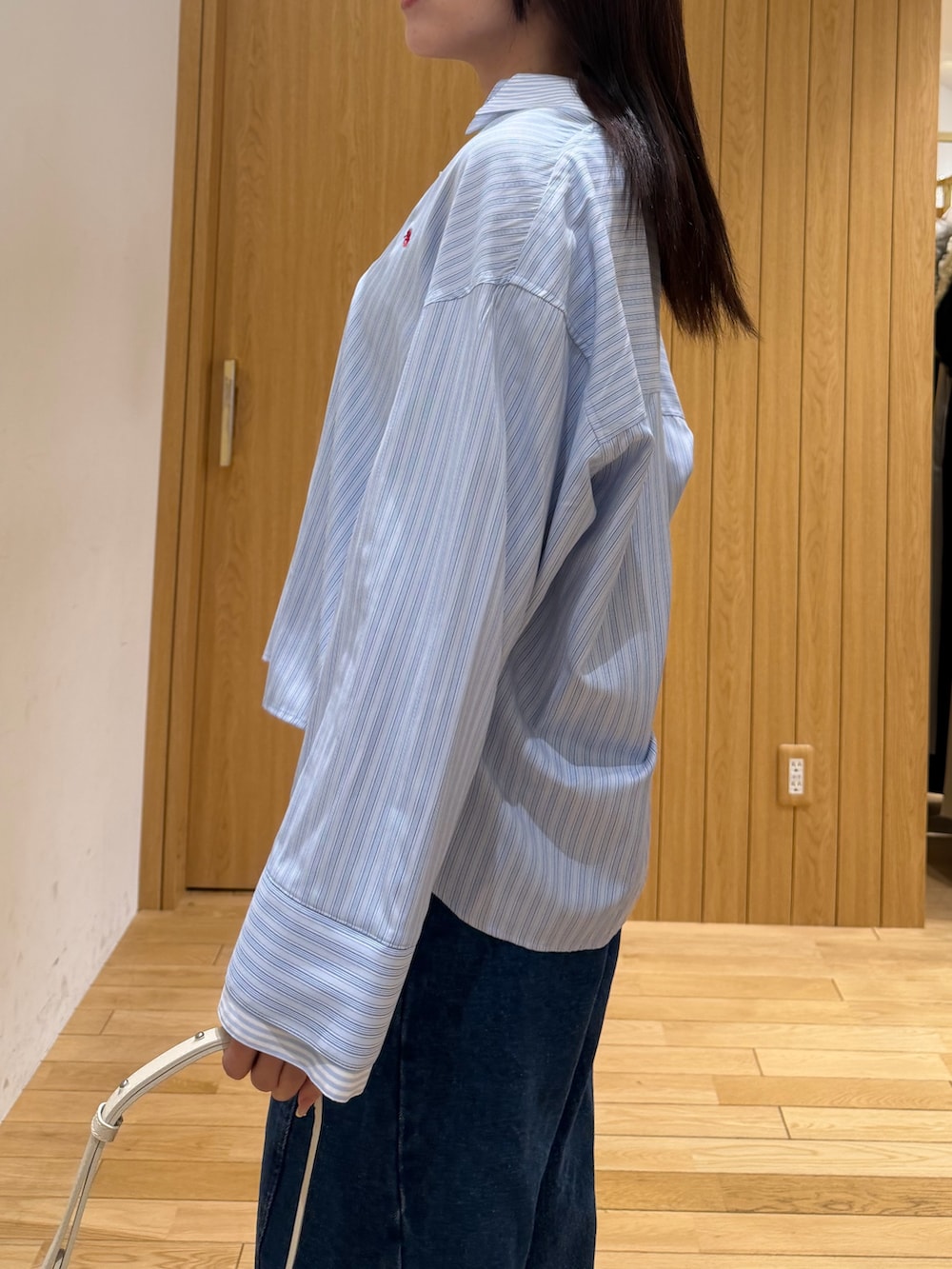 ブルー系のデニムパンツ、ブルー系のシャツ/ブラウス、ホワイト系のハンドバッグを着用したレディースの春コーディネートの5枚目の写真