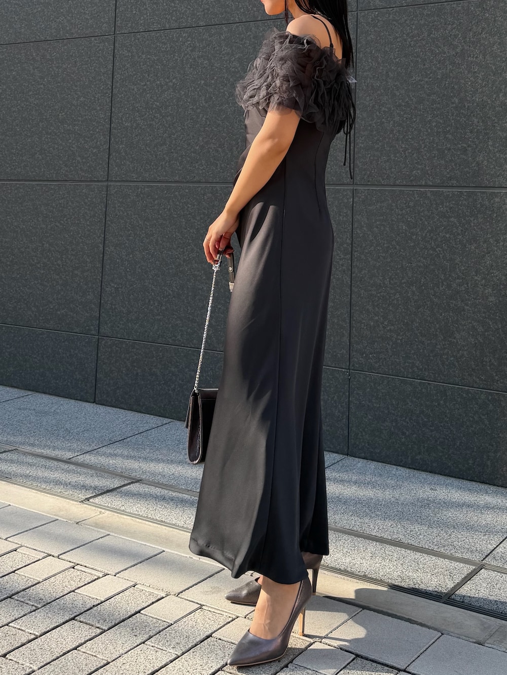 シルバー系のクラッチバッグ、シルバー系のパンプス、グレー系のドレスを着用したレディースの冬コーディネートの5枚目の写真