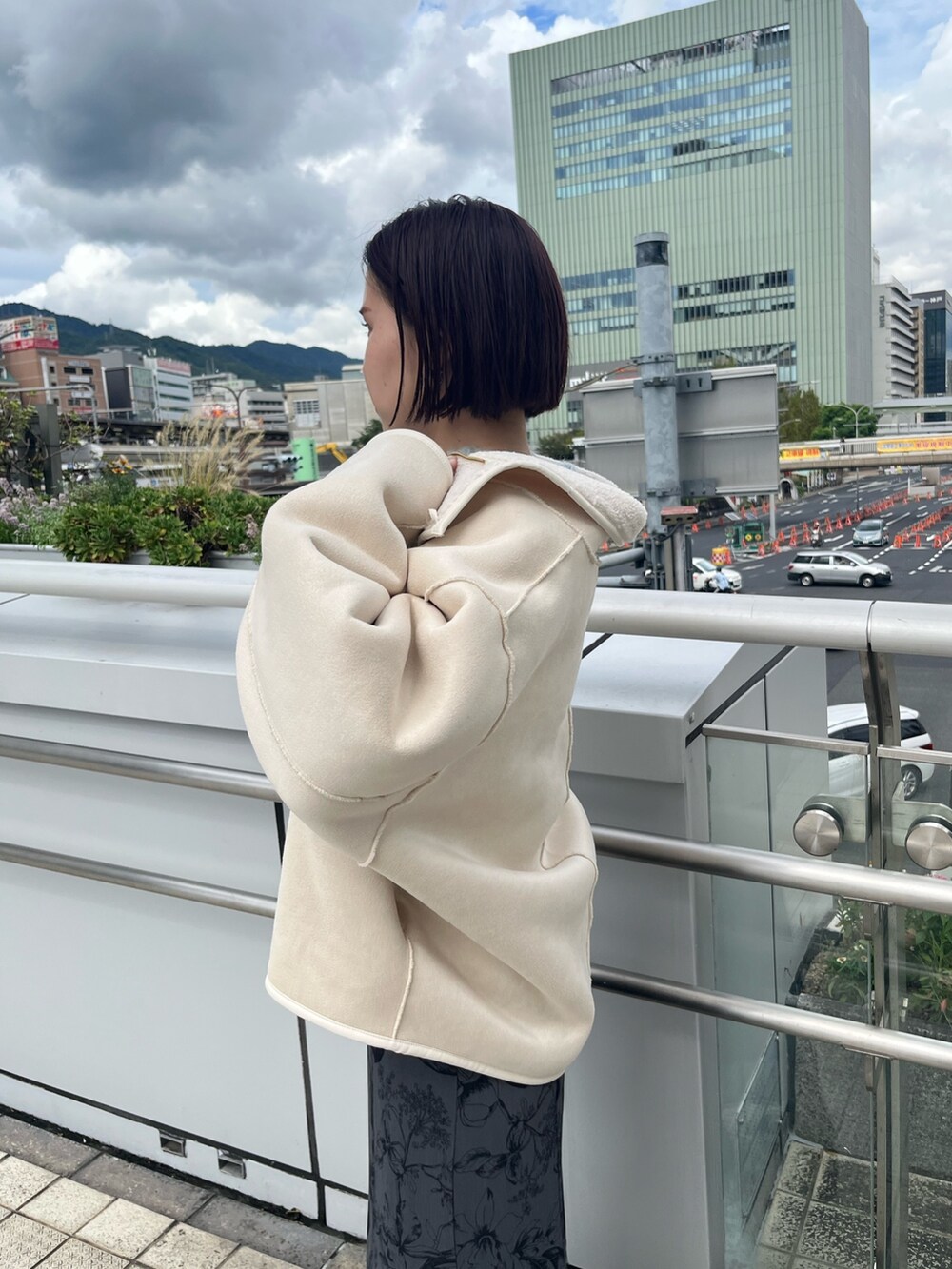 ホワイト系のムートンコート、グリーン系のニット/セーター、グレー系のスカートを着用したレディースの秋コーディネートの5枚目の写真