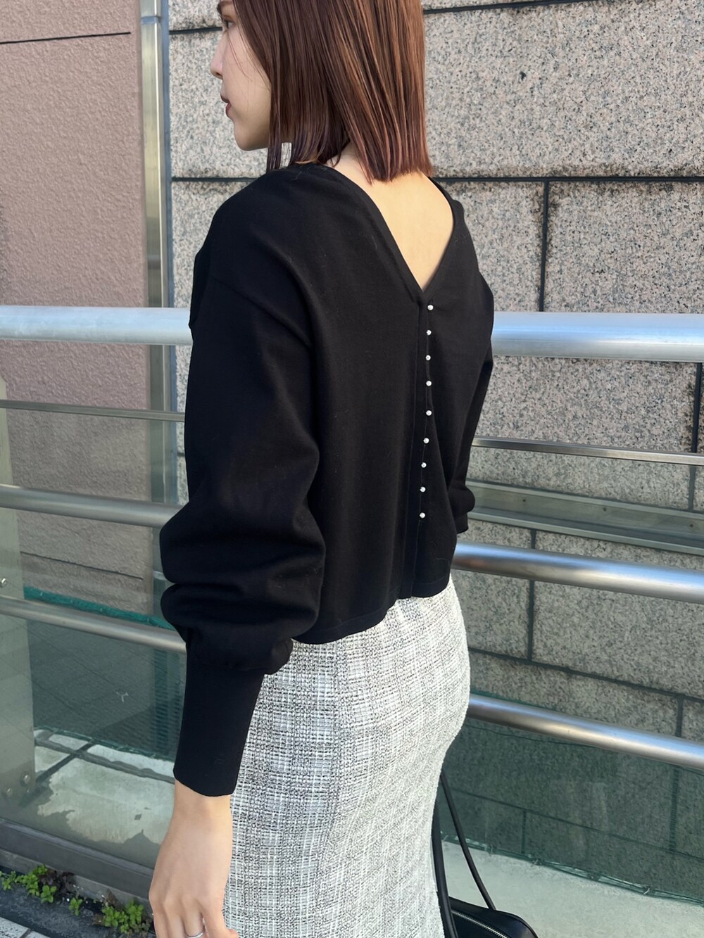 ホワイト系のスカート、ブラック系のニット/セーター、ブラック系のショルダーバッグを着用したレディースの冬コーディネートの6枚目の写真