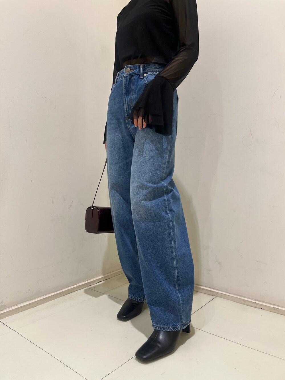 ブルー系のデニムパンツ、レッド系のショルダーバッグ、ブラック系のブーツを着用したレディースの秋コーディネートの5枚目の写真