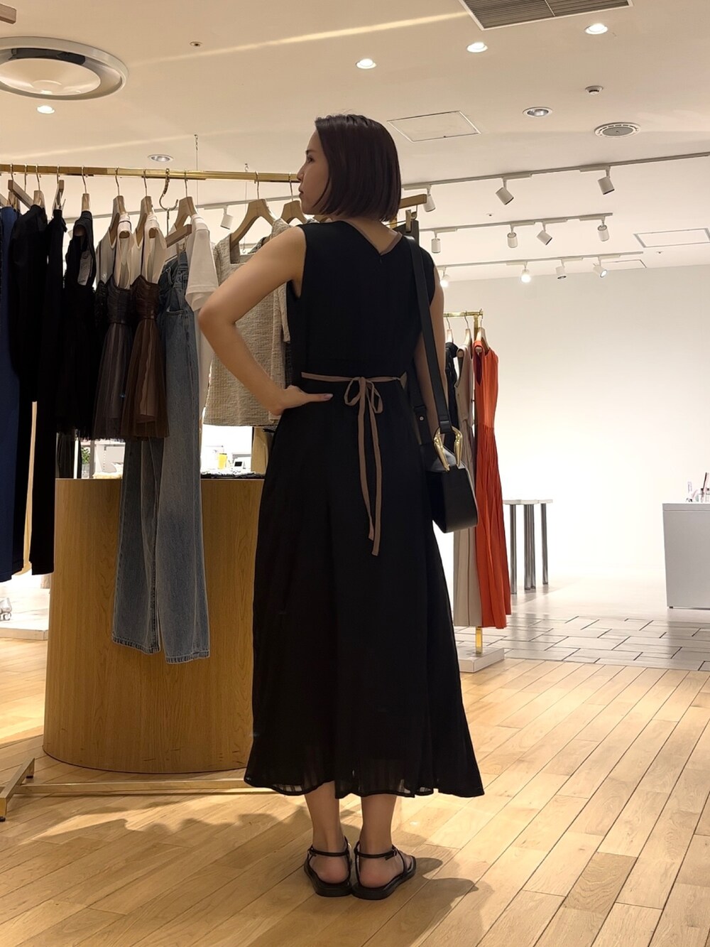 ブラック系のワンピース、ブラック系のサンダル、ホワイト系のシャツ/ブラウスを着用したレディースの夏コーディネートの3枚目の写真