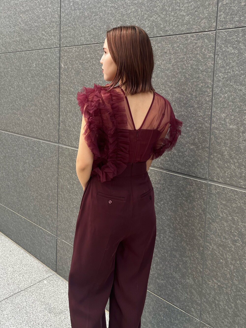 シルバー系のハンドバッグ、レッド系のパンツドレスを着用したレディースの冬コーディネートの6枚目の写真
