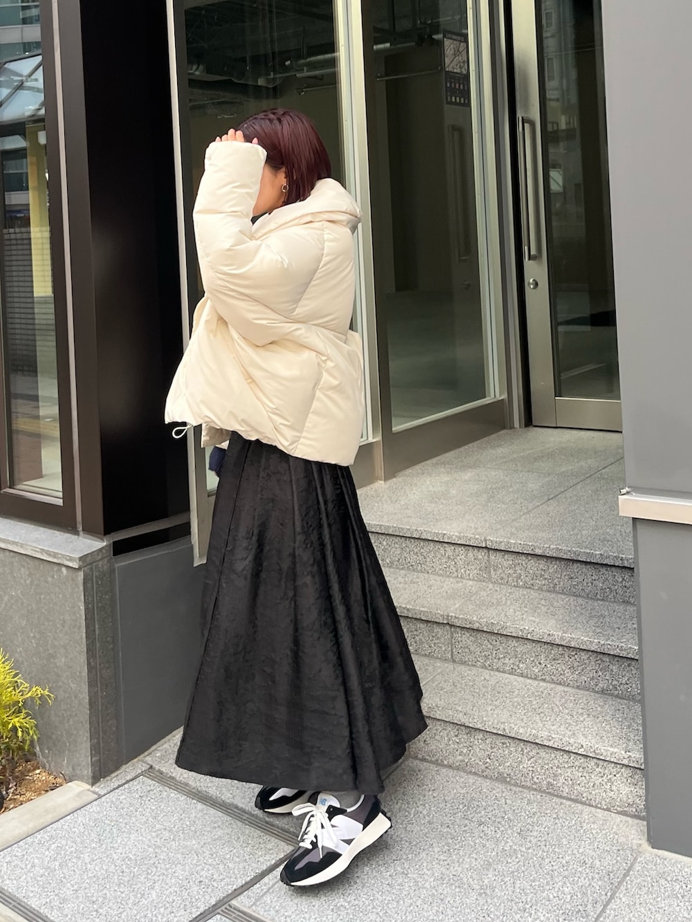 ホワイト系のダウンジャケット/コート、ブルー系のニット/セーター、ブラック系のスカートを着用したレディースの冬コーディネートの4枚目の写真