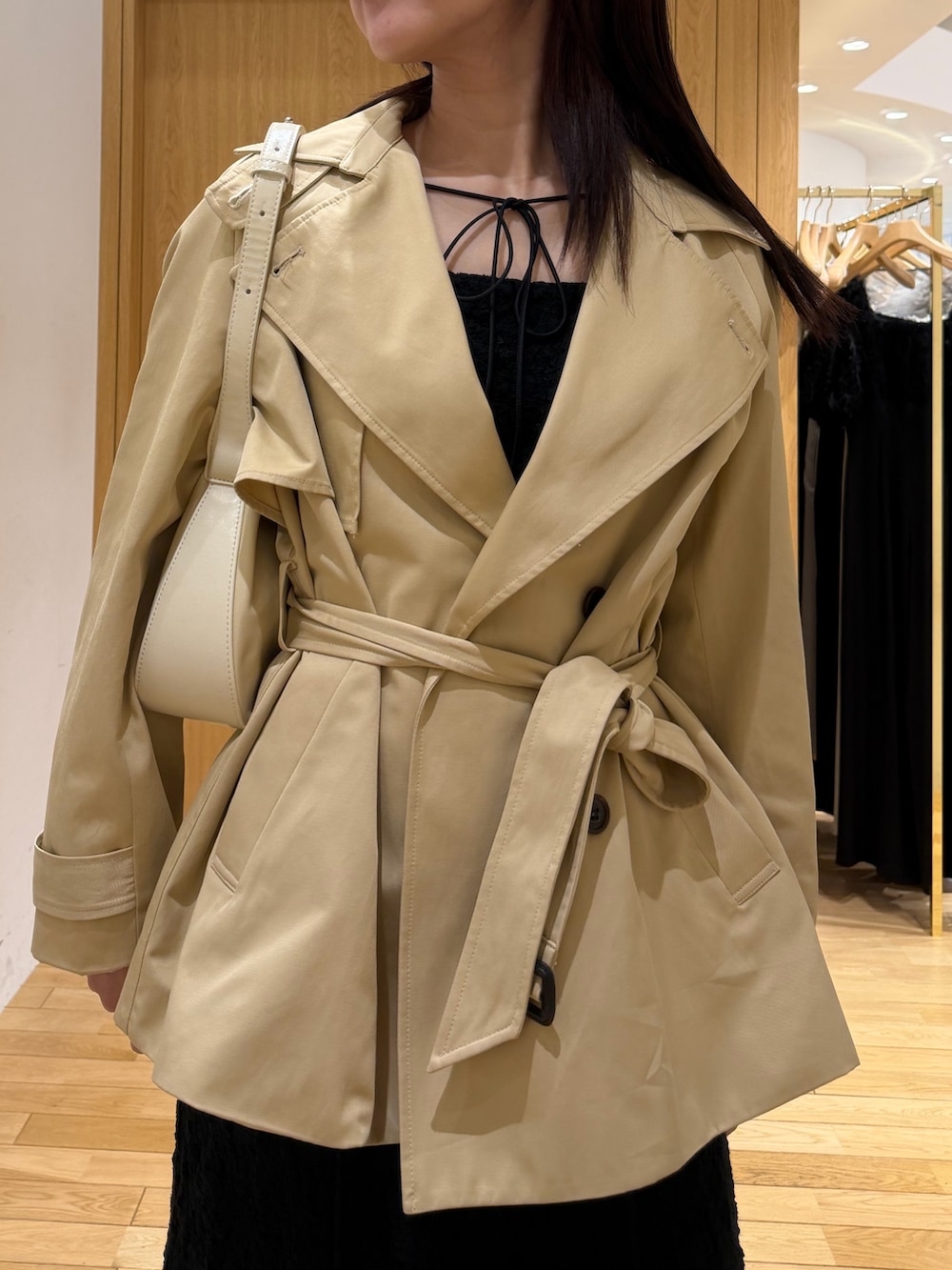 ブラック系のワンピース、ベージュ系のトレンチコートを着用したレディースの春コーディネートの3枚目の写真