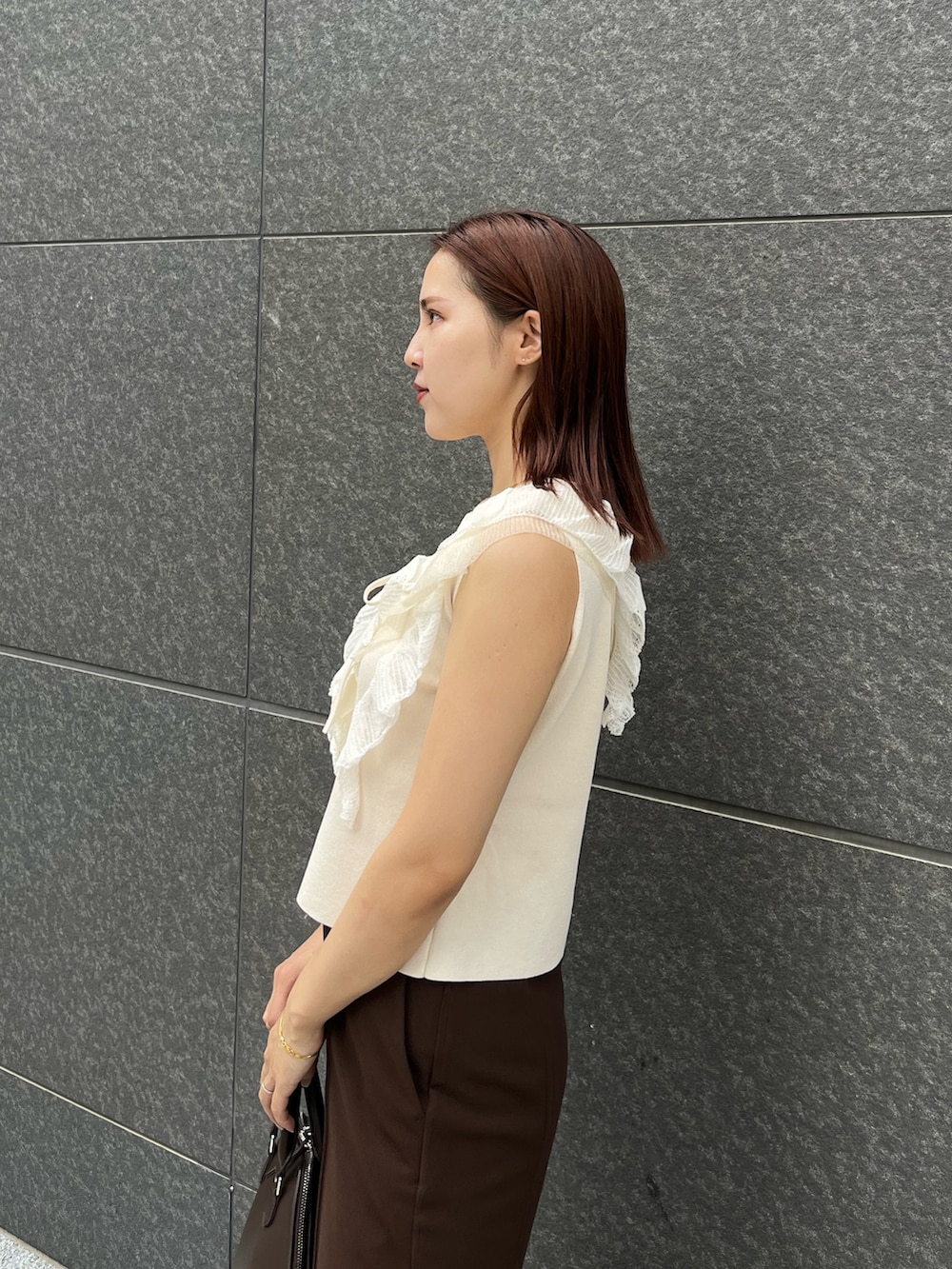 ホワイト系のニット/セーター、ブラウン系のその他パンツ、ブラウン系のボストンバッグを着用したレディースの夏コーディネートの6枚目の写真