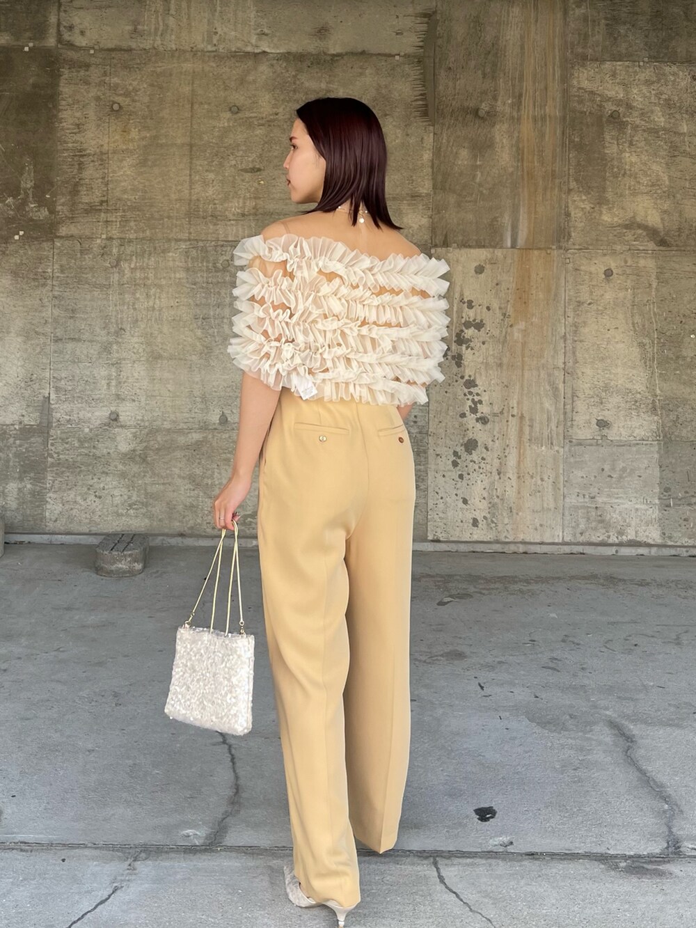 イエロー系のパンツドレス、ベージュ系のショルダーバッグ、ベージュ系のパンプスを着用したレディースの春コーディネートの3枚目の写真