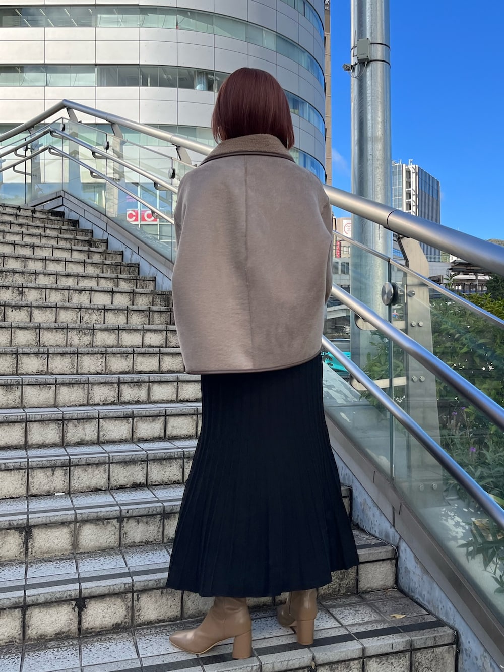 ブラック系のワンピース、ベージュ系のブーツ、ブラック系のハンドバッグを着用したレディースの秋コーディネートの3枚目の写真