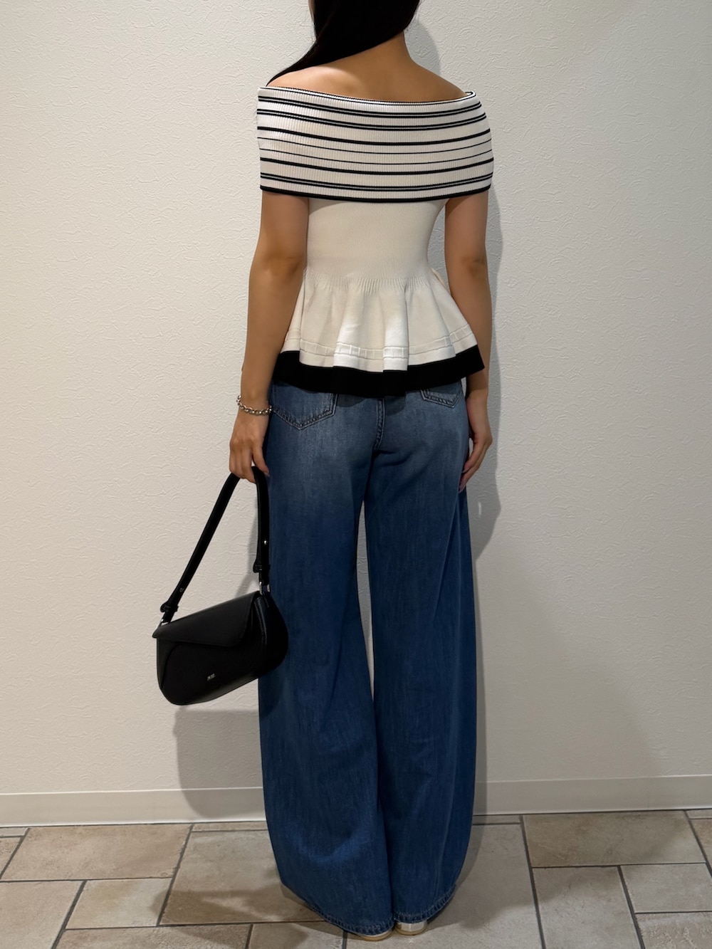 ブルー系のデニムパンツ、ブラック系のハンドバッグ、グリーン系のパンプスを着用したレディースの夏コーディネートの3枚目の写真
