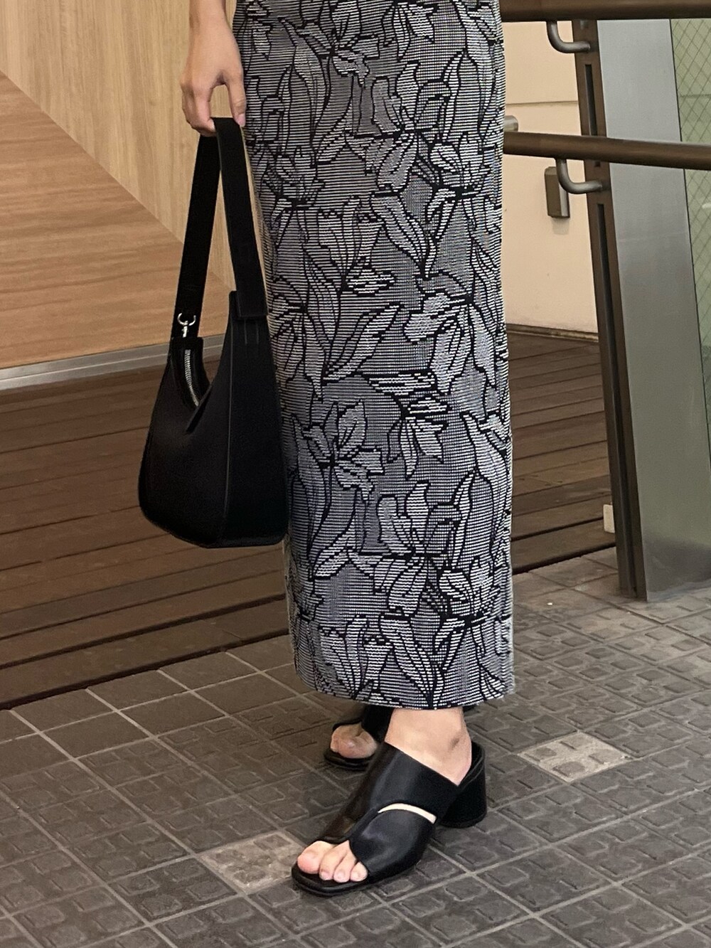 ブラック系のハンドバッグ、ブラック系のサンダル、ブラック系のスカートを着用したレディースの春コーディネートの6枚目の写真