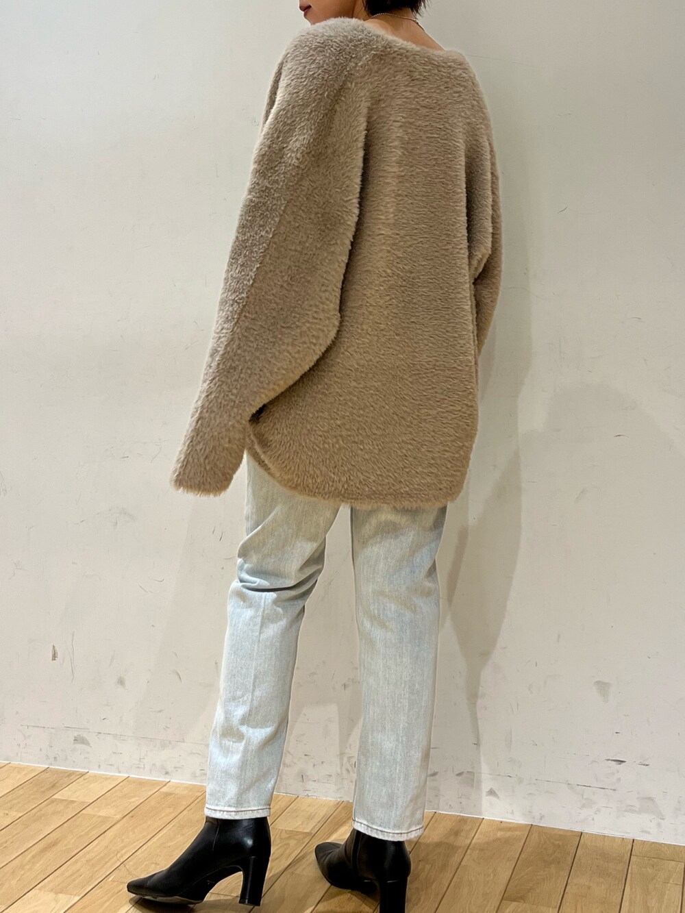 ブルー系のデニムパンツ、ホワイト系のニット/セーター、ブラウン系のカーディガン/ボレロを着用したレディースの秋コーディネートの3枚目の写真