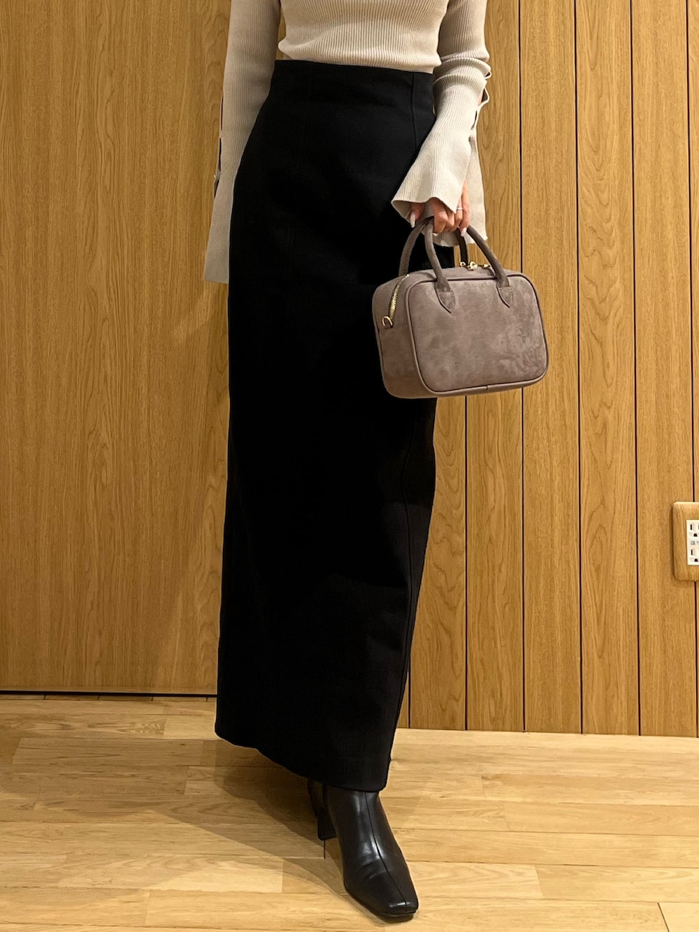 ブラック系のスカート、ベージュ系のニット/セーター、ブラウン系のハンドバッグを着用したレディースの秋コーディネートの6枚目の写真