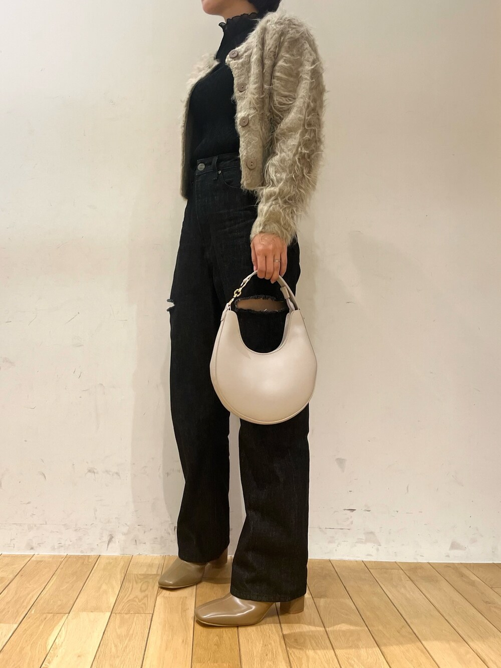 ホワイト系のハンドバッグ、ブラック系のデニムパンツ、ベージュ系のブーツを着用したレディースの秋コーディネートの5枚目の写真
