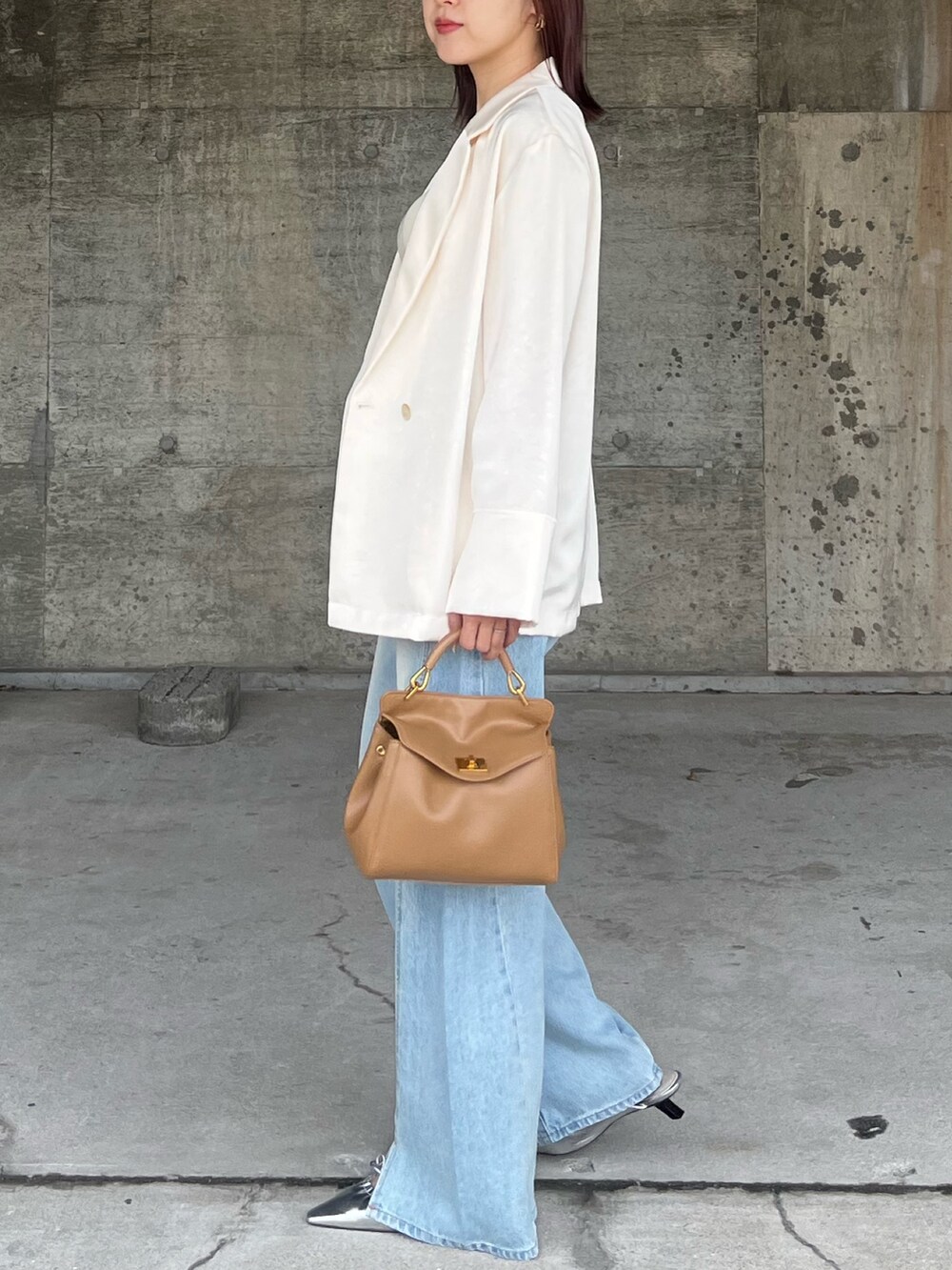 ブルー系のデニムパンツ、シルバー系のサンダル、ブラウン系のハンドバッグを着用したレディースの春コーディネートの2枚目の写真