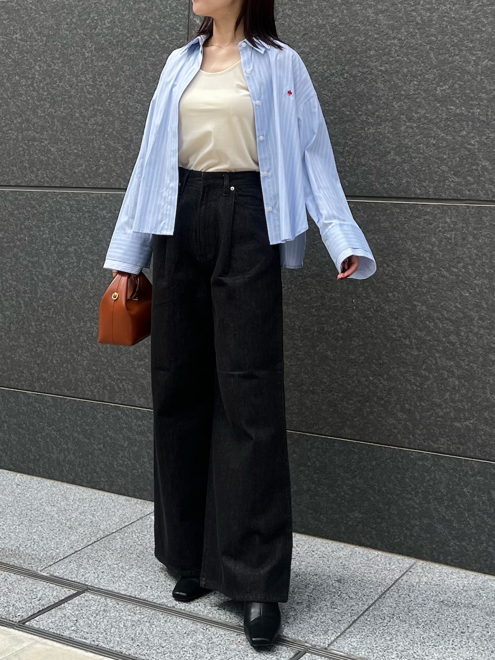 ブラック系のブーツ、ブラック系のデニムパンツ、レッド系のハンドバッグを着用したレディースの秋コーディネートの4枚目の写真