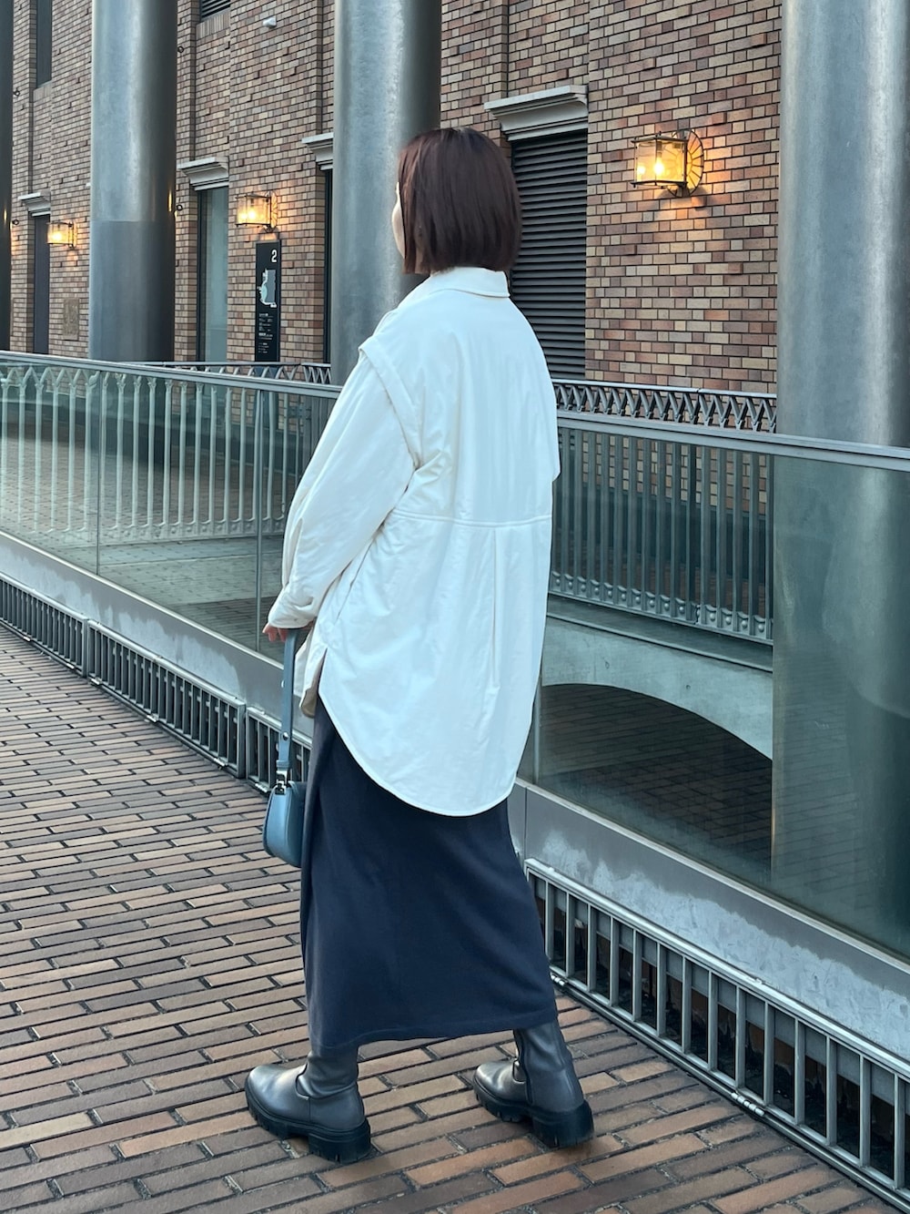 ブルー系のショルダーバッグ、グレー系のスカート、ホワイト系のブルゾンを着用したレディースの冬コーディネートの3枚目の写真