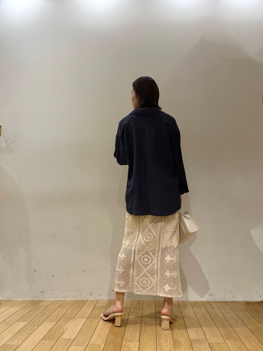 ホワイト系のニット/セーター、ホワイト系のショルダーバッグ、ブルー系のシャツ/ブラウスを着用したレディースの春コーディネートの3枚目の写真