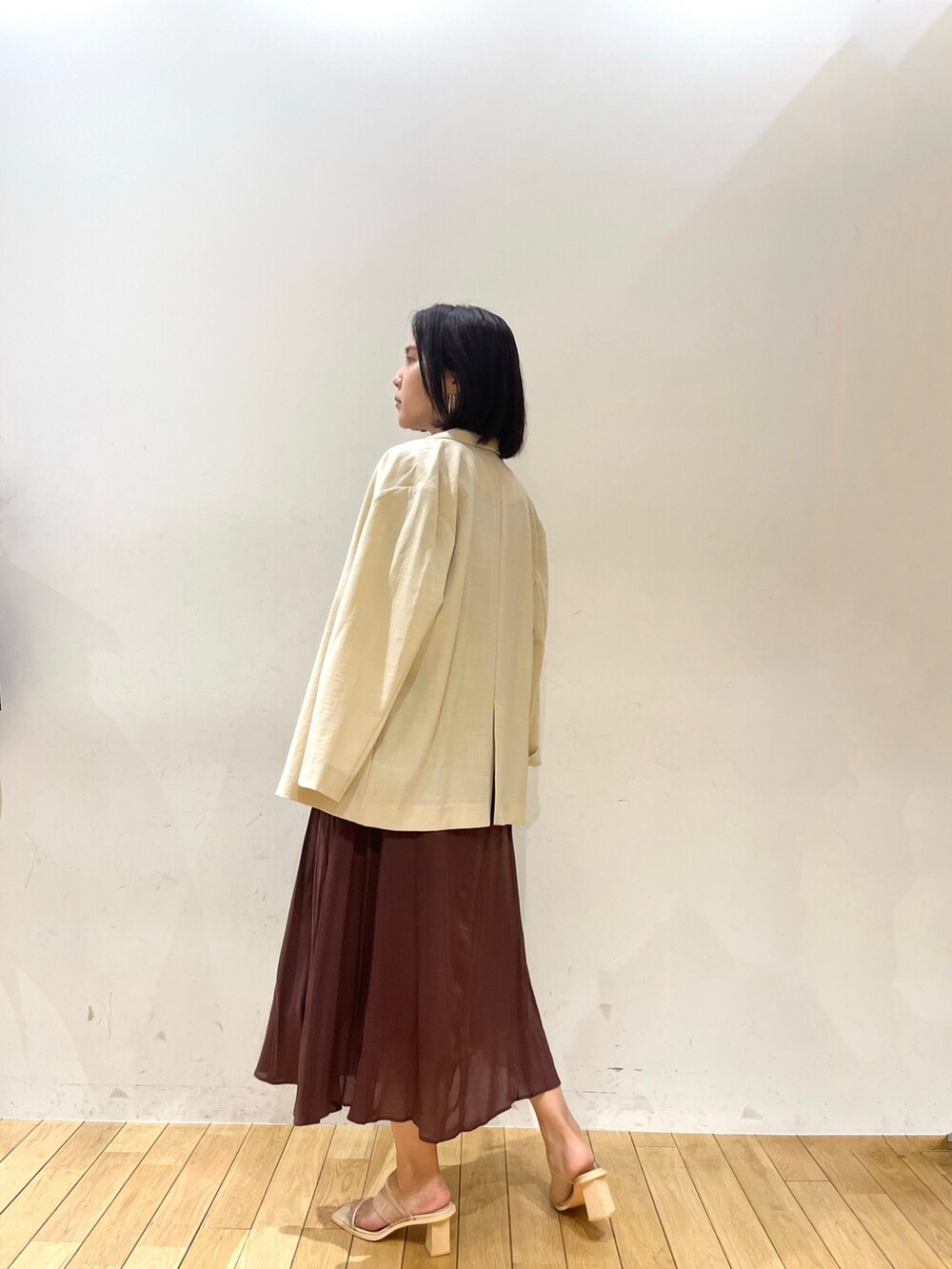 ブラウン系のワンピース、その他のサンダル、ベージュ系のテーラードジャケットを着用したレディースの夏コーディネートの2枚目の写真