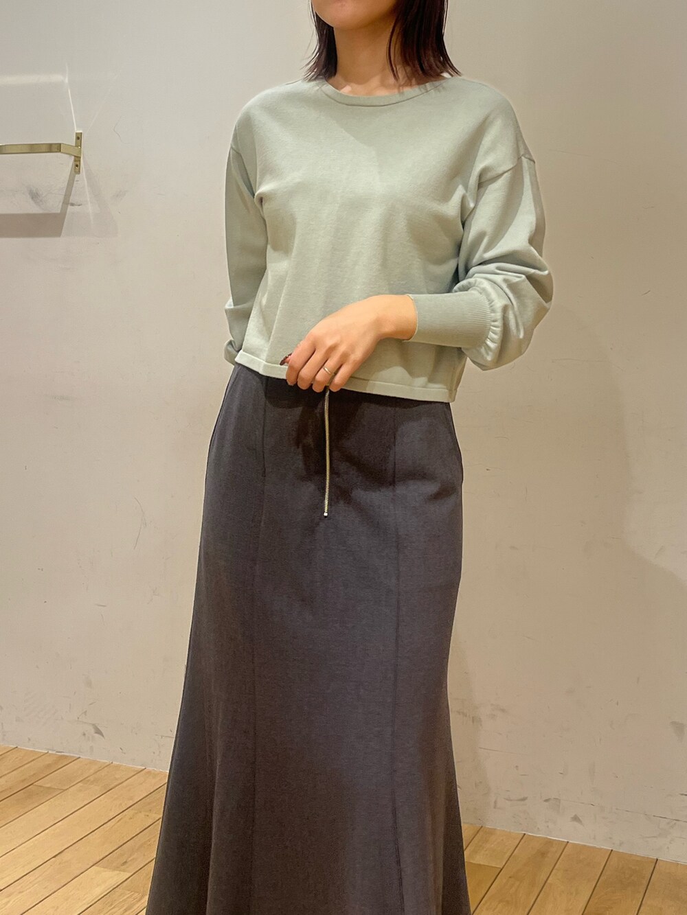 グリーン系のニット/セーター、グレー系のスカート、ブラック系のブーツを着用したレディースの冬コーディネートの4枚目の写真