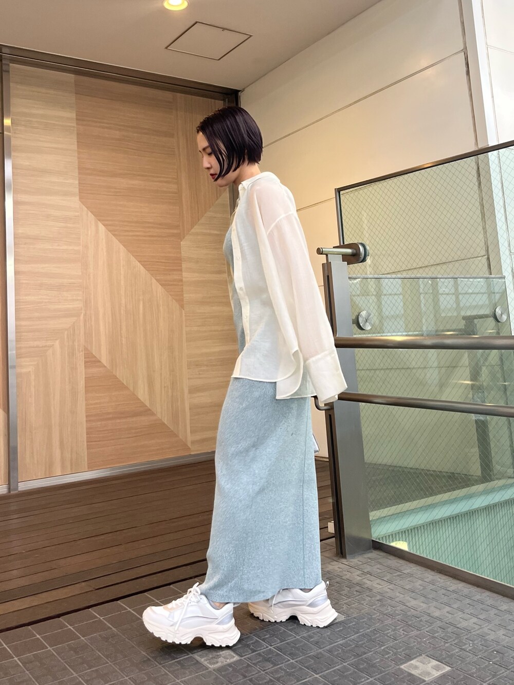 シルバー系のショルダーバッグ、ホワイト系のスニーカー、ブルー系のワンピースを着用したレディースの春コーディネートの2枚目の写真