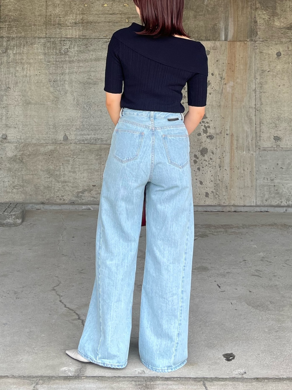 ブルー系のデニムパンツ、ブルー系のニット/セーター、レッド系のハンドバッグを着用したレディースの春コーディネートの3枚目の写真