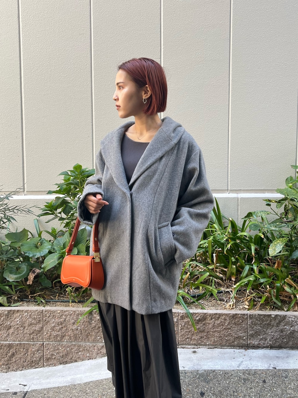 グレー系のワンピース、オレンジ系のショルダーバッグ、グレー系のその他アウターを着用したレディースの秋コーディネートの2枚目の写真