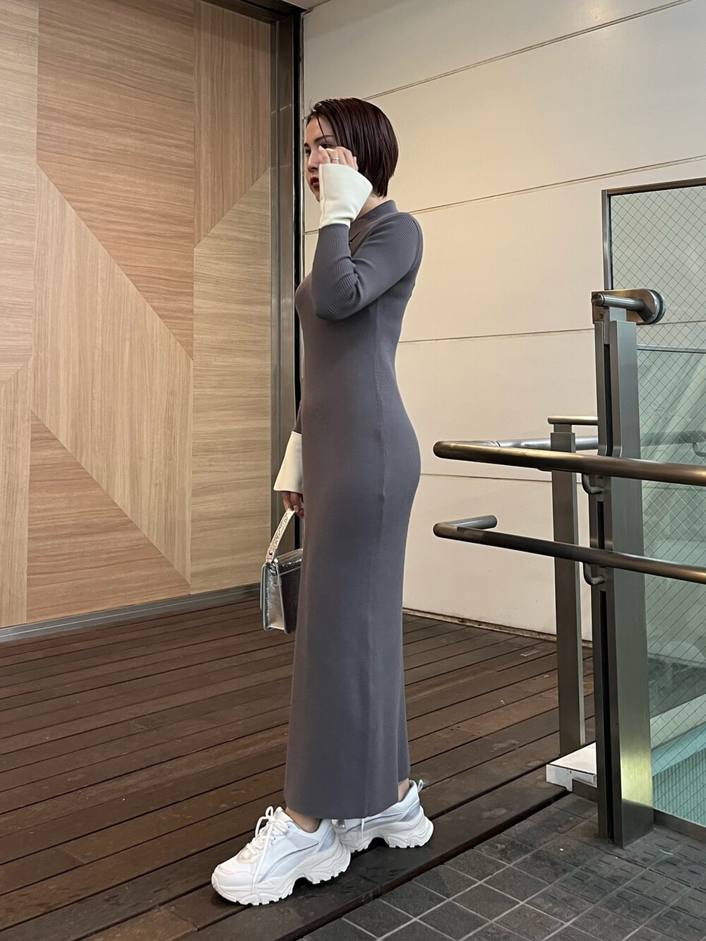 グレー系のワンピース、ホワイト系のスニーカー、シルバー系のショルダーバッグを着用したレディースの冬コーディネートの3枚目の写真