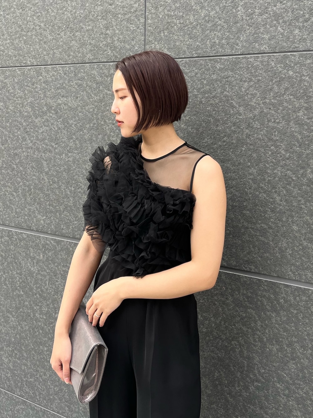 シルバー系のハンドバッグ、ブラック系のパンツドレス、シルバー系のパンプスを着用したレディースの春コーディネートの7枚目の写真