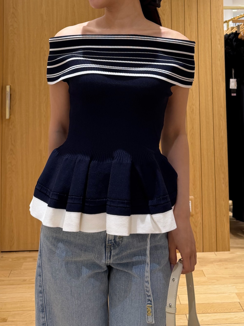 ブルー系のデニムパンツ、ホワイト系のハンドバッグ、ホワイト系のサンダルを着用したレディースの夏コーディネートの4枚目の写真