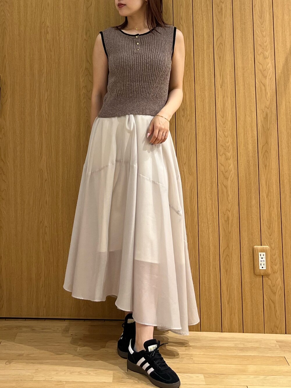 ブラウン系のニット/セーター、グレー系のスカート、ブラック系のスニーカーを着用したレディースの春コーディネートの4枚目の写真