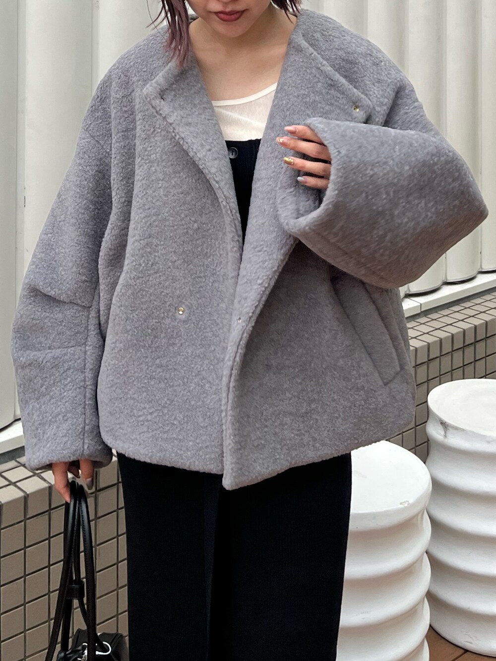 グレー系のブルゾン、ホワイト系のTシャツ/カットソー、ブラック系のショルダーバッグを着用したレディースの秋コーディネートの4枚目の写真