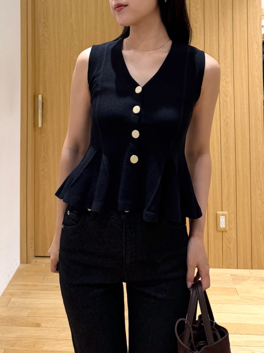 ブラック系のデニムパンツ、ブラック系のニット/セーター、ブラウン系のハンドバッグを着用したレディースの夏コーディネートの4枚目の写真