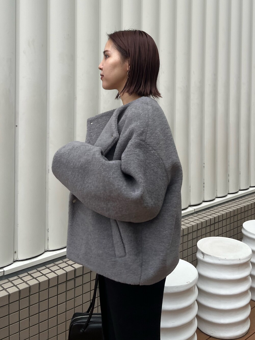グレー系のブルゾン、ホワイト系のTシャツ/カットソー、ブラック系のショルダーバッグを着用したレディースの秋コーディネートの5枚目の写真