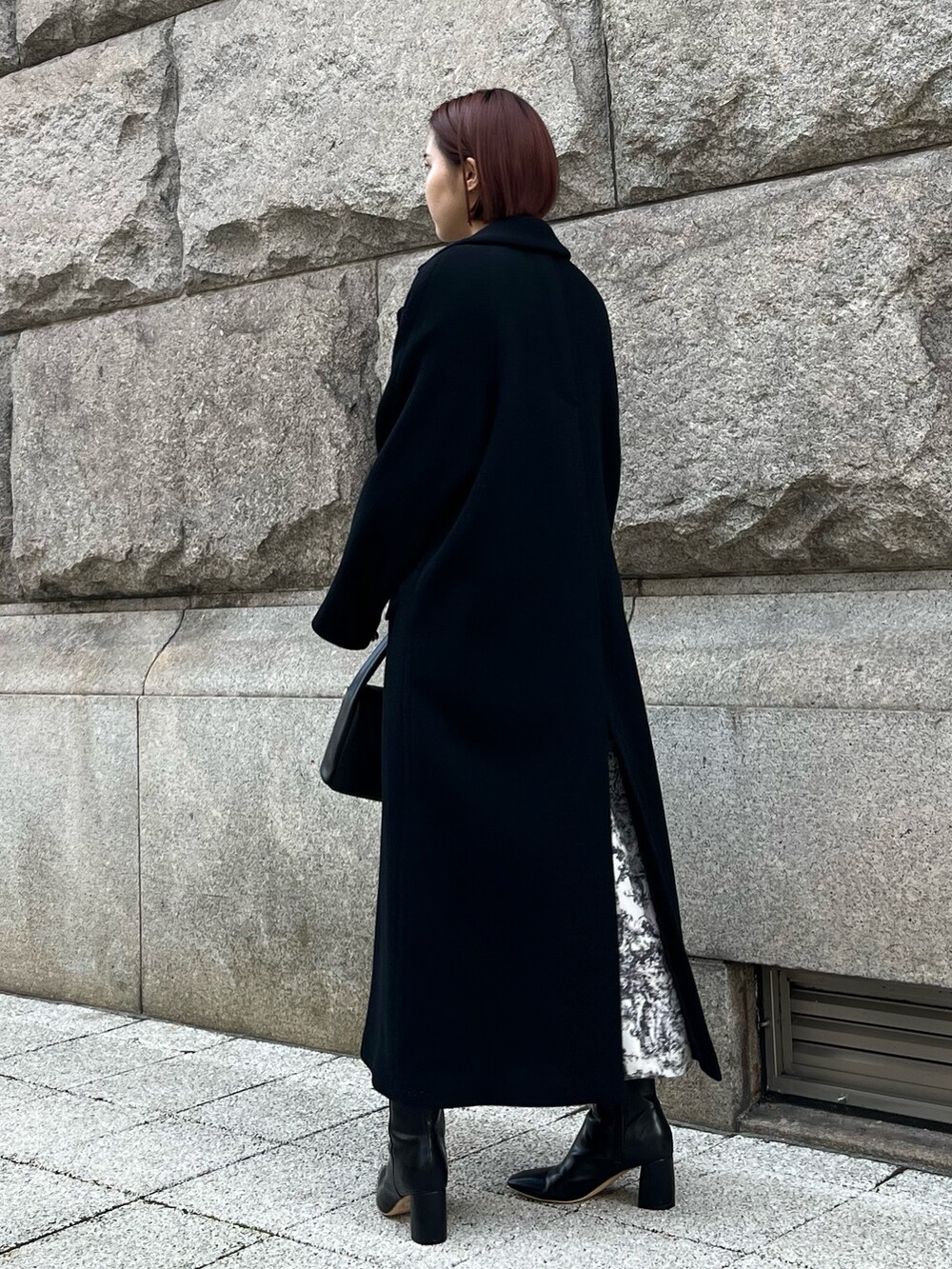 ホワイト系のワンピース、ブラック系のチェスターコート、ブラック系のハンドバッグを着用したレディースの冬コーディネートの5枚目の写真
