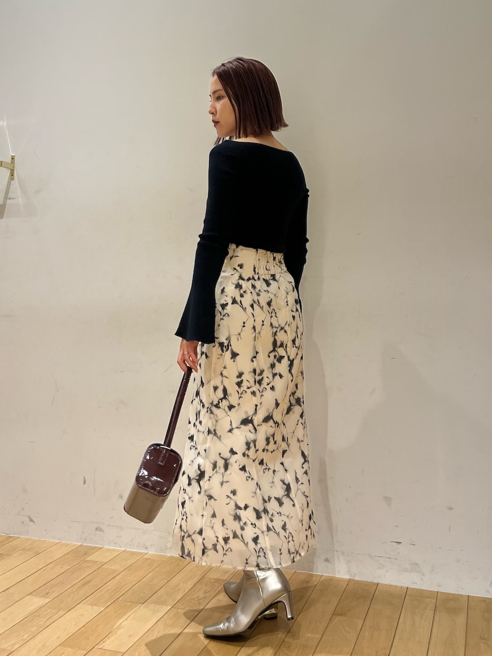 レッド系のショルダーバッグ、ホワイト系のスカート、シルバー系のブーツを着用したレディースの秋コーディネートの3枚目の写真