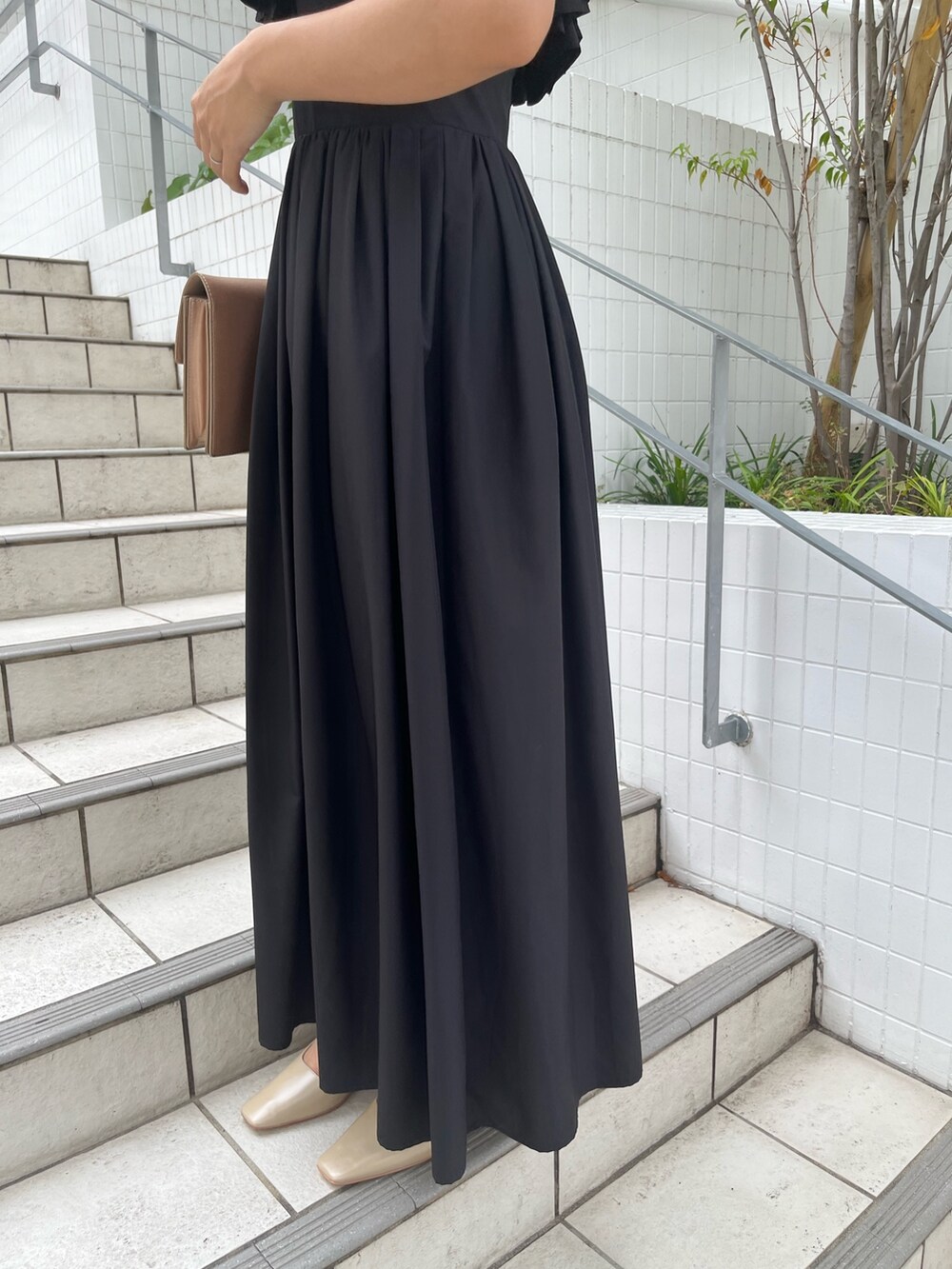 ブラック系のドレス、ベージュ系のクラッチバッグ、ベージュ系のパンプスを着用したレディースの秋コーディネートの6枚目の写真