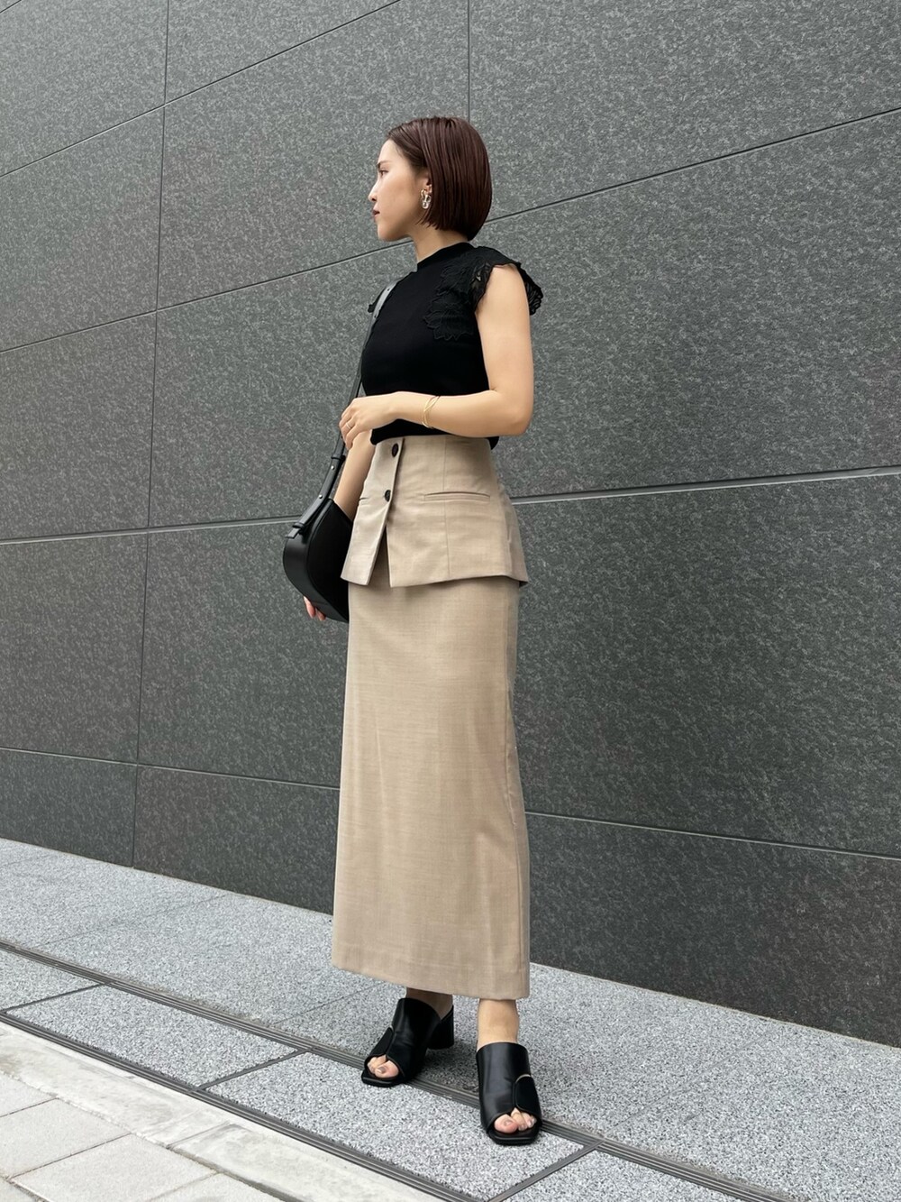 ブラック系のサンダル、ブラック系のニット/セーター、ベージュ系のスカートを着用したレディースの春コーディネートの2枚目の写真