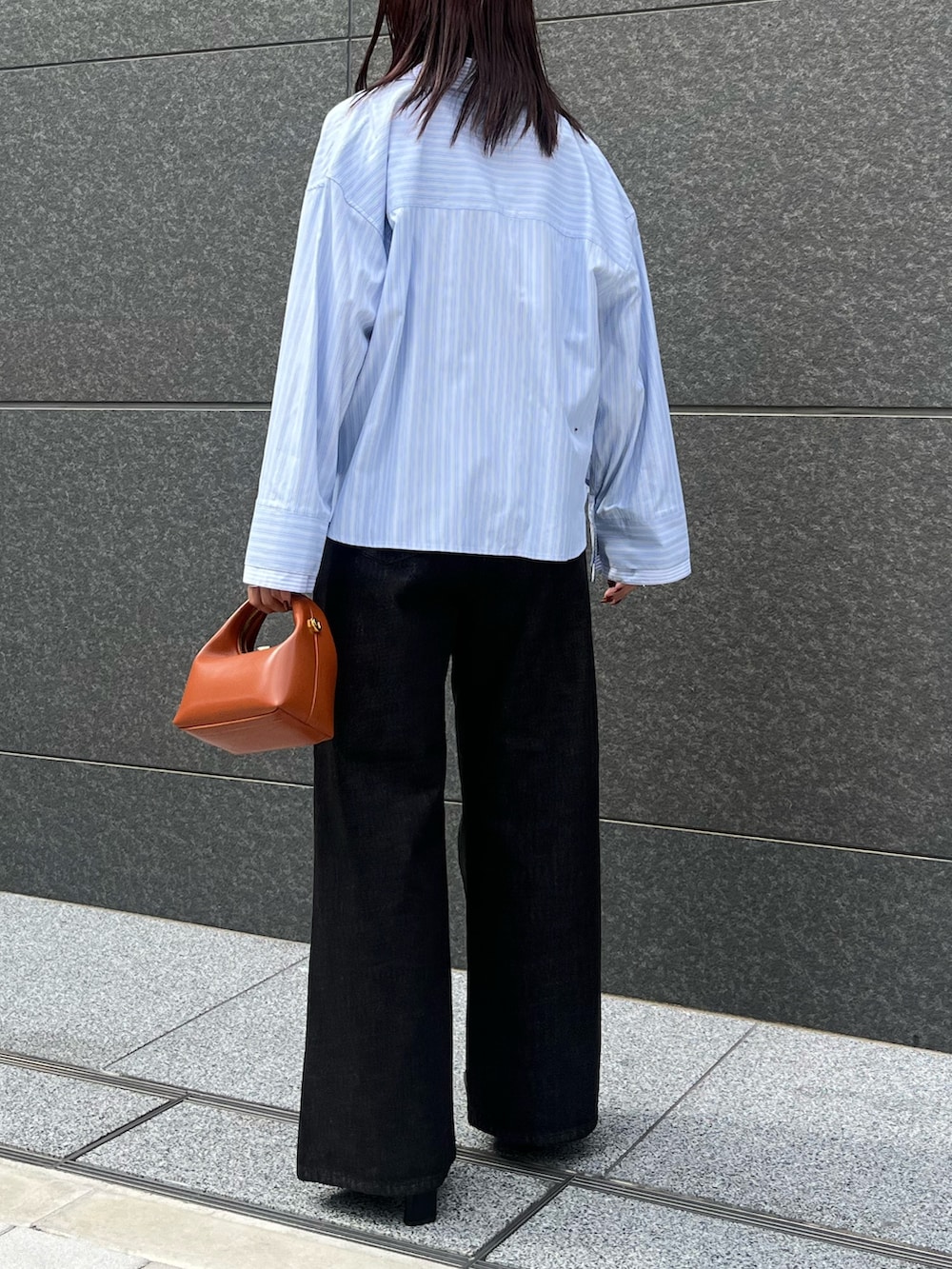 ブラック系のブーツ、ブラック系のデニムパンツ、レッド系のハンドバッグを着用したレディースの秋コーディネートの3枚目の写真