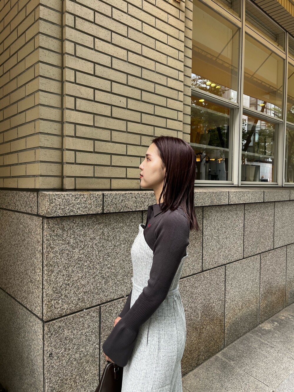 グレー系のワンピース、ブラウン系のボストンバッグ、ブラック系のブーツを着用したレディースの秋コーディネートの5枚目の写真