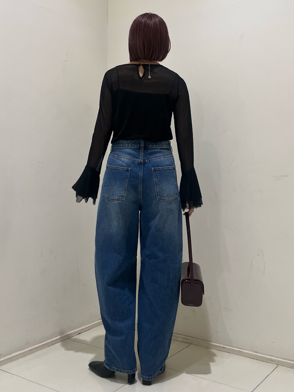 ブルー系のデニムパンツ、レッド系のショルダーバッグ、ブラック系のブーツを着用したレディースの秋コーディネートの4枚目の写真