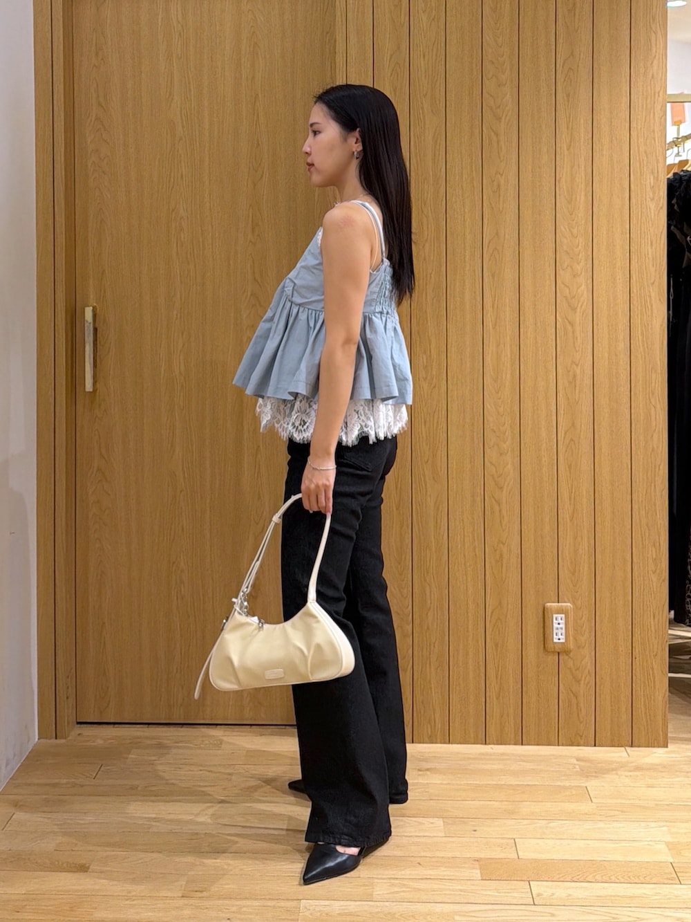 ブラック系のデニムパンツ、ホワイト系のハンドバッグ、ブルー系のキャミソールを着用したレディースの夏コーディネートの2枚目の写真