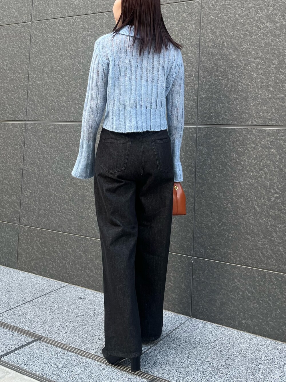 ブルー系のニット/セーター、ブラック系のデニムパンツ、ブラウン系のハンドバッグを着用したレディースの秋コーディネートの3枚目の写真