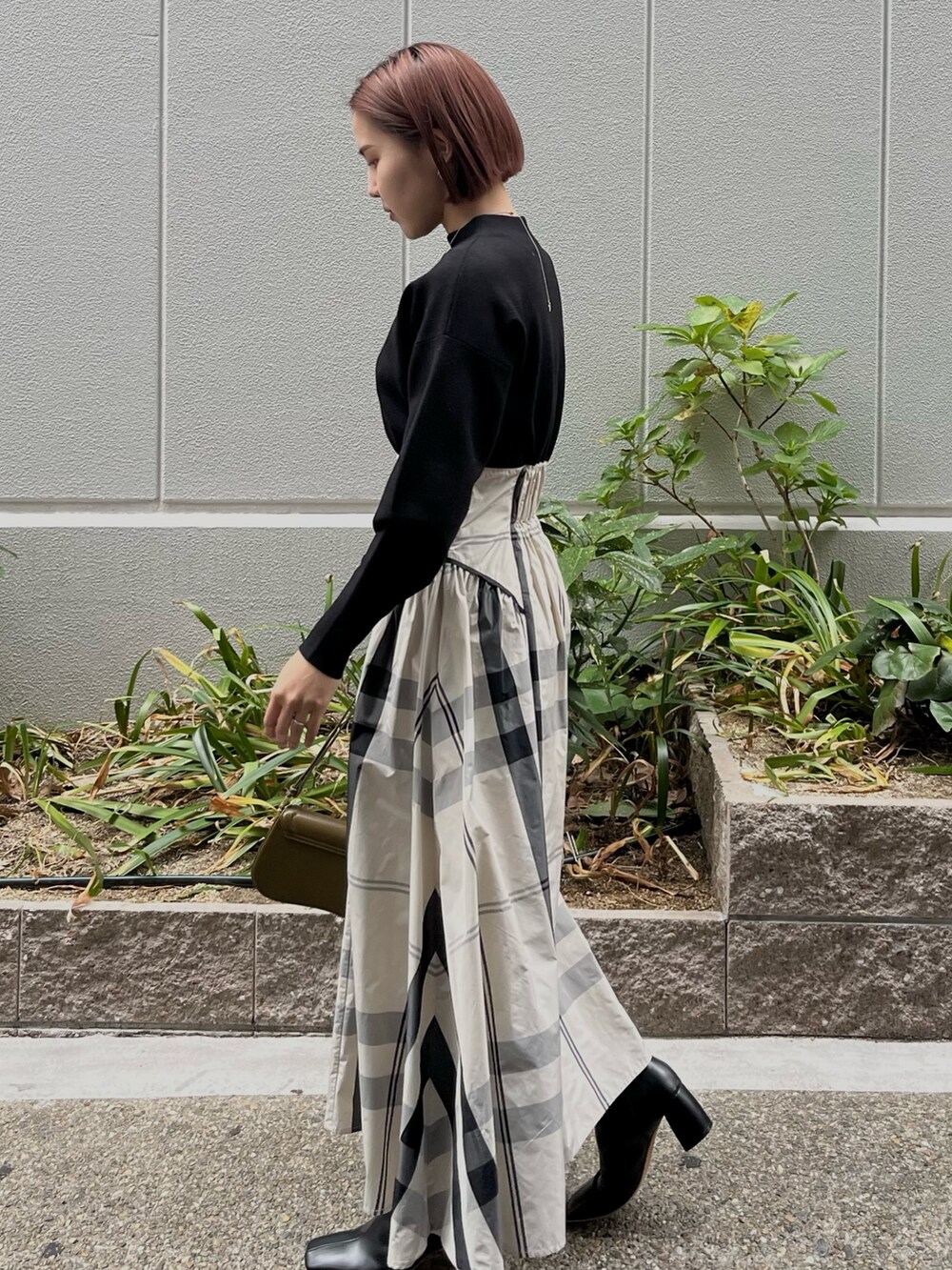 ホワイト系のワンピース、ブラック系のブーツ、ブラウン系のショルダーバッグを着用したレディースの冬コーディネートの2枚目の写真