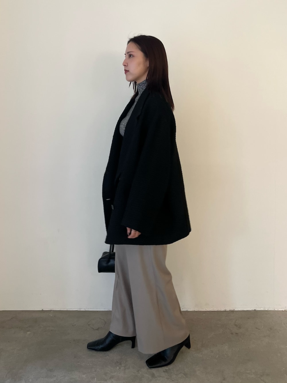 ブラック系のブーツ、ブラック系のニット/セーター、ブラック系のその他アウターを着用したレディースの冬コーディネートの2枚目の写真