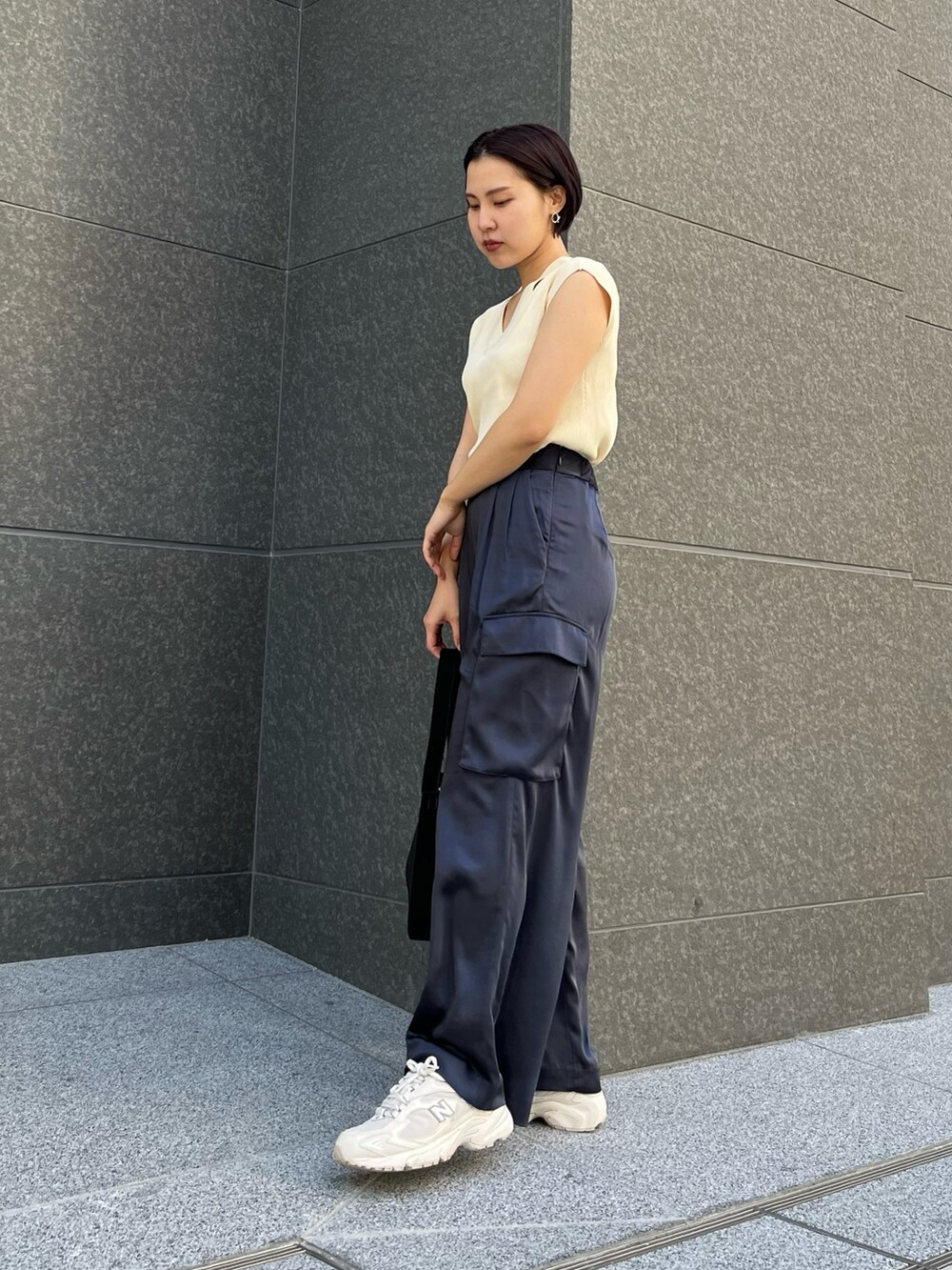 ブラック系のハンドバッグ、ブルー系のカーゴパンツ、ホワイト系のニット/セーターを着用したレディースの春コーディネートの3枚目の写真