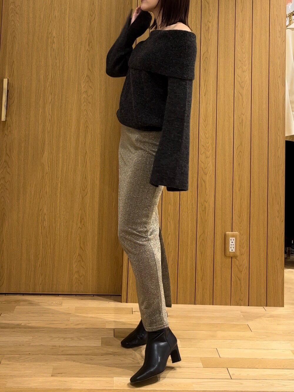 ゴールド系のスカート、ブラック系のブーツ、グレー系のニット/セーターを着用したレディースの冬コーディネートの2枚目の写真