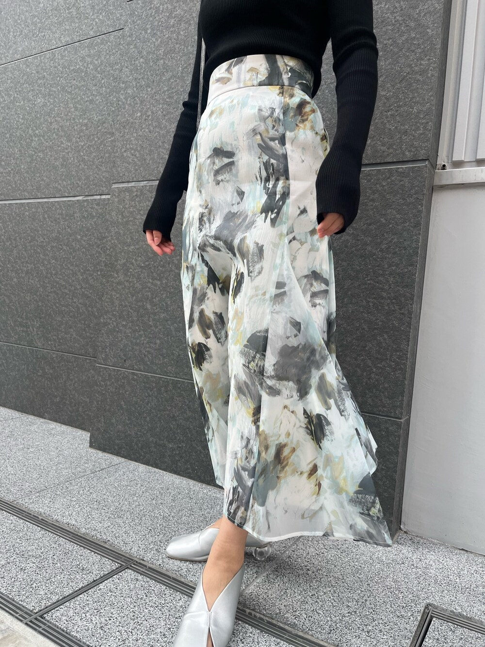 ブルー系のスカート、シルバー系のパンプス、ブラック系のハンドバッグを着用したレディースの春コーディネートの5枚目の写真