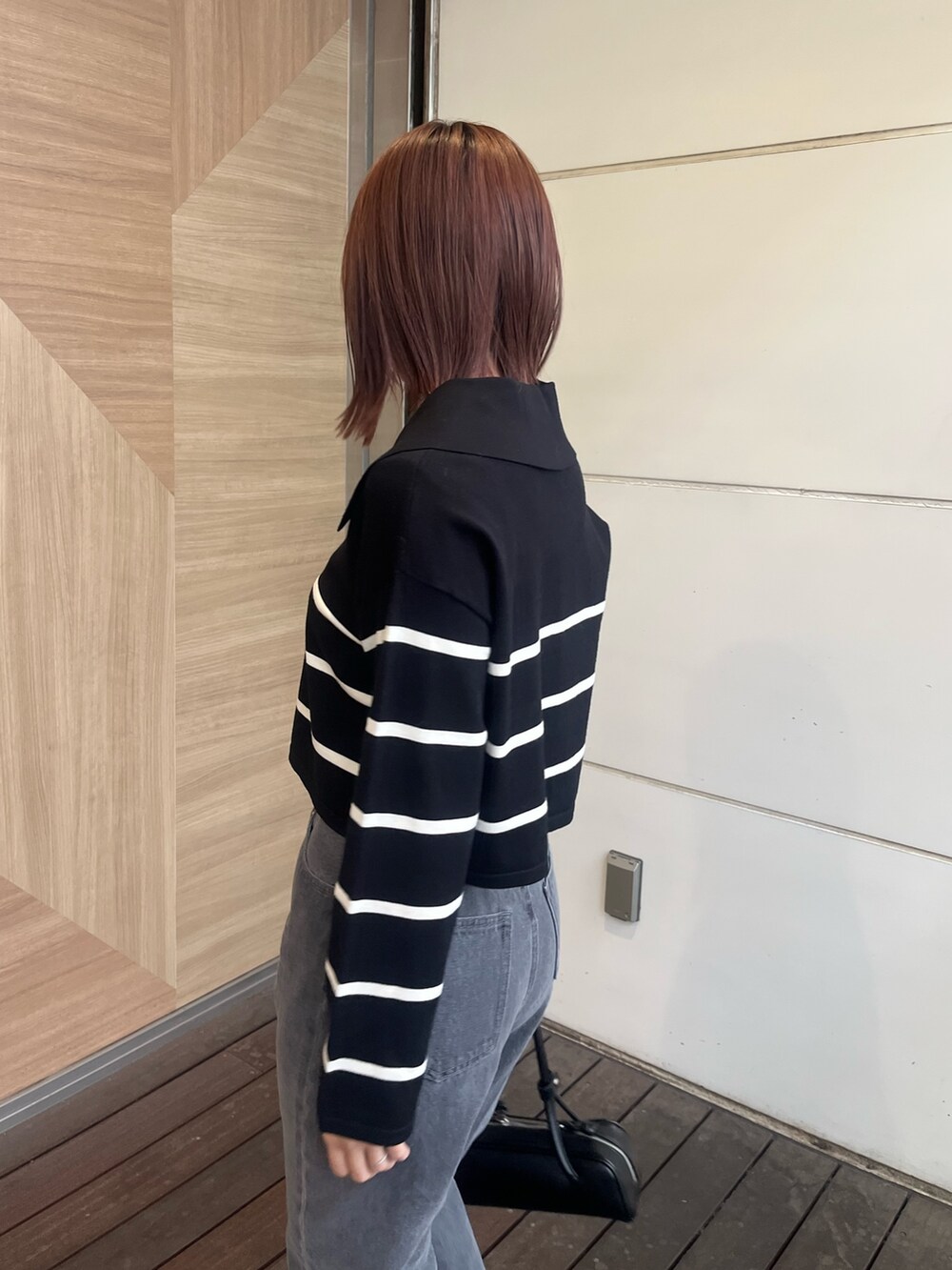 ブラック系のデニムパンツ、ブラック系のニット/セーター、ブラック系のショルダーバッグを着用したレディースの冬コーディネートの5枚目の写真